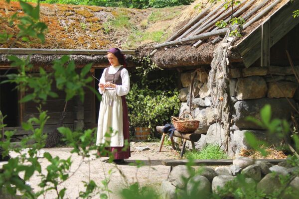 En historiskt klädd kvinna står framför Hornborgarstugan.