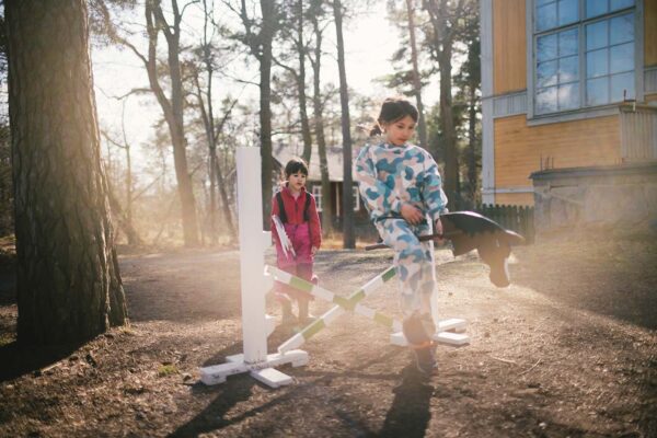 Två barn rider käpphäst på käpphästbanan utanför Kronbergs Atlejé.