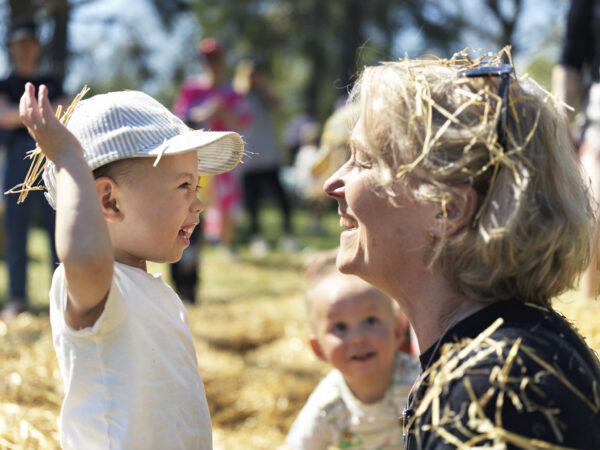 Barn och kvinna leker i hö 